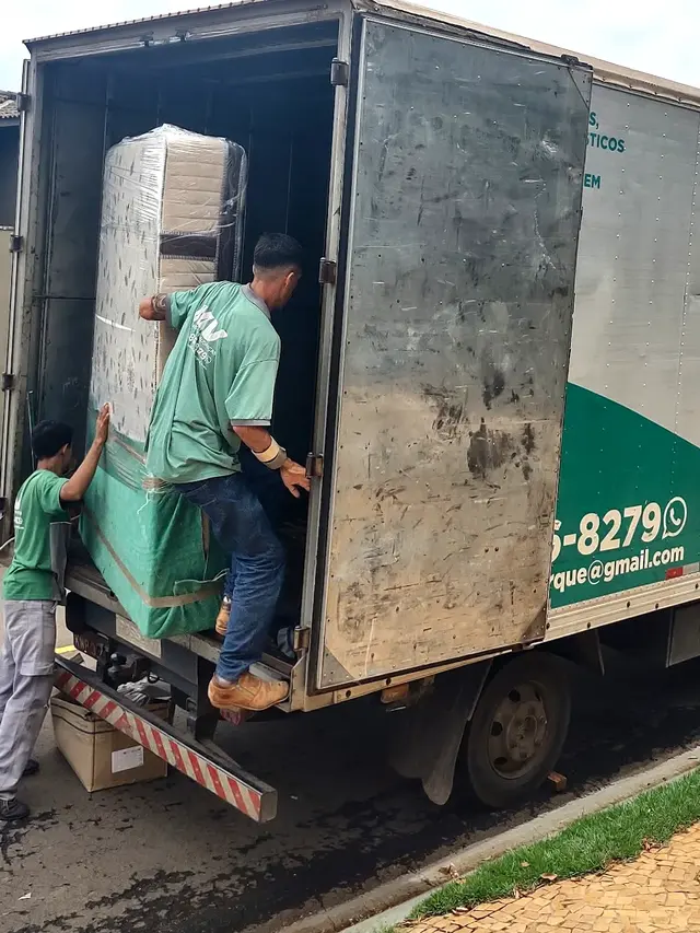 Equipe da MV Transportes carregando colchão embalado no caminhão baú
