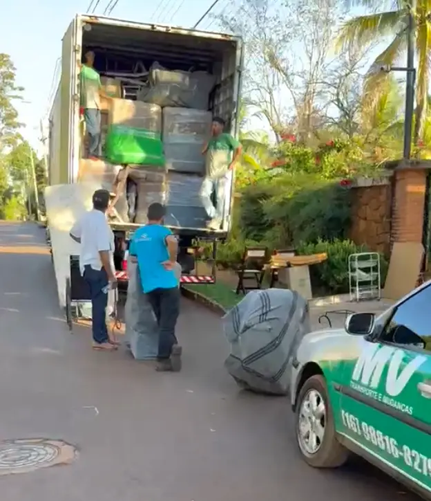 Equipe da MV Transportes carregando móveis embalados no caminhão baú durante uma mudança